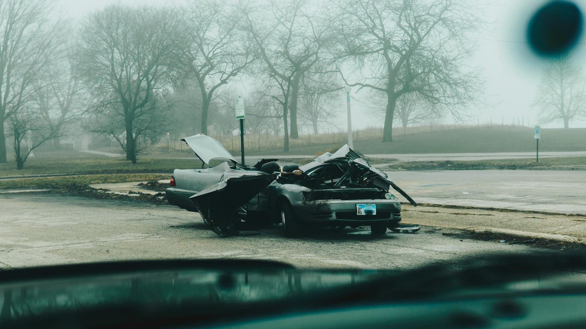 A foggy morning with a severely damaged car on a deserted street in Chicago.